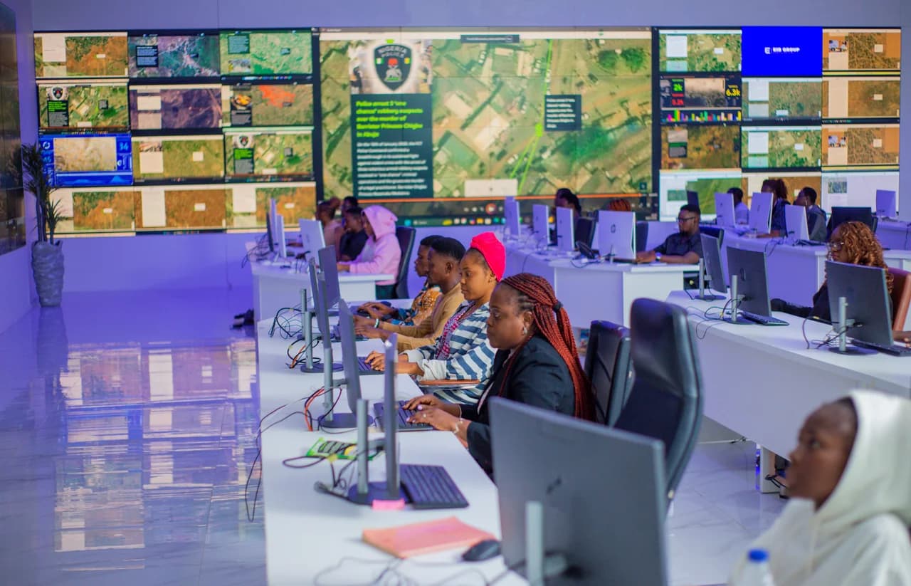 Operations team working at consoles beneath a wall of monitoring screens